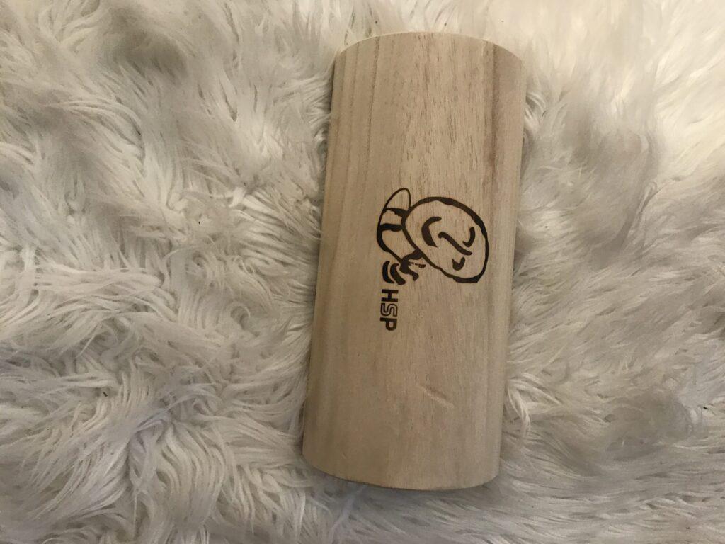 Wooden tumbler with a logo on a soft white surface.